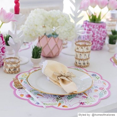 Table setting with bunny scalloped round paper placemats layered with a gold and white plate and yellow napkin