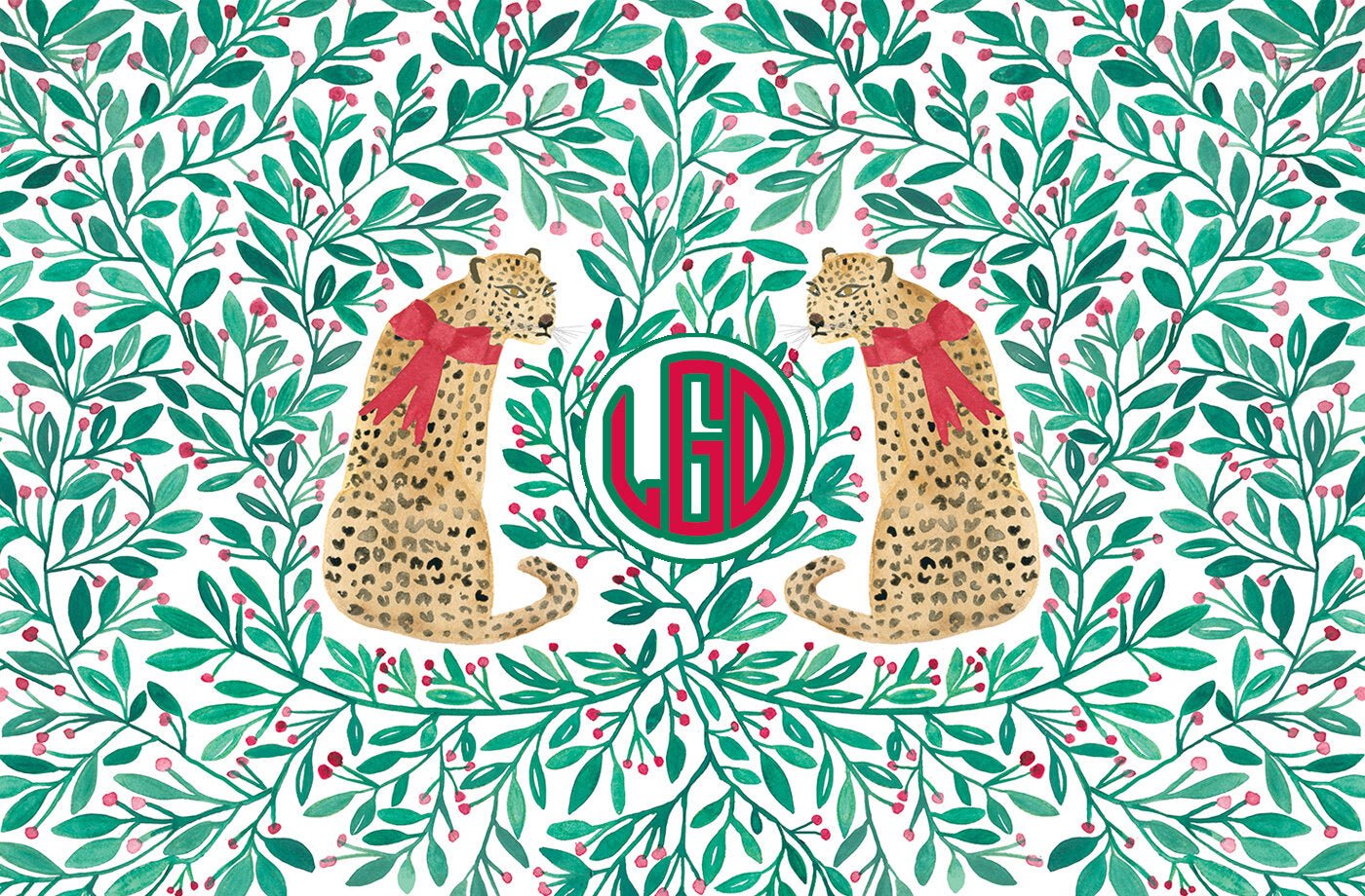 Paper placemat featuring a red and green holly berry pattern with leopards and a red and green monogram