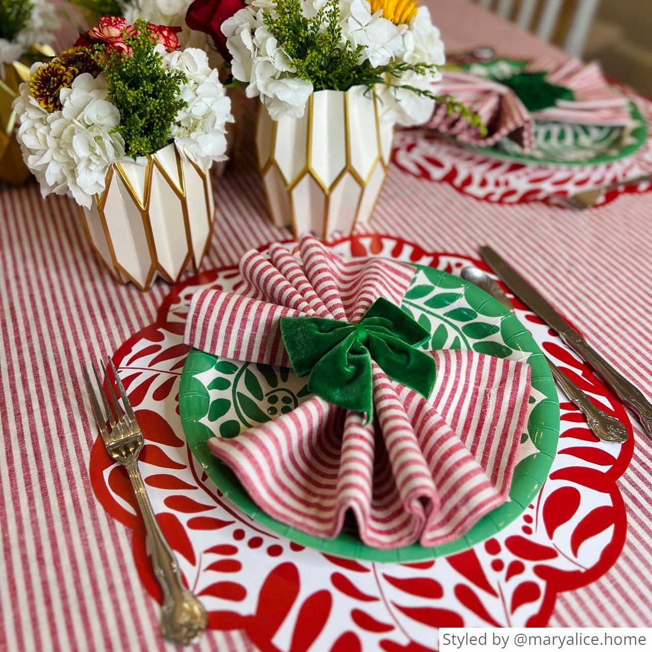 Holiday themed tablescape featuring our green heavy duty paper plates, green velvet bow napkin rings, and gold and white paper vase wraps
