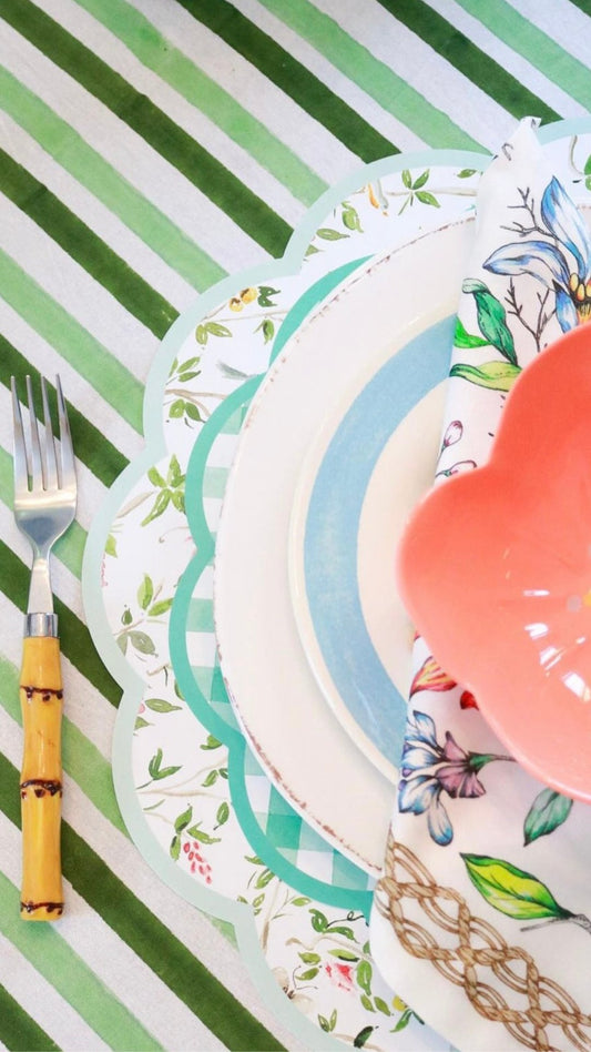 Layered spring table setting for Mother's Day brunch with paper placemats and dishes.