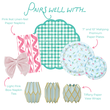 Product assortment including pink ikat paper napkins, teal checkered placemats, floral paper plates, light pink bow napkin ties, and decorative paper vase wraps on a white background