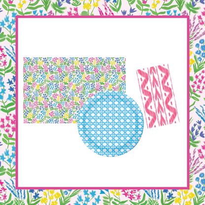 Pairs well with graphic: Floral wildflower paper placemat in pink-bordered pastel garden print, blue dotted grid heavy-duty paper plate, and pink ikat patterned paper napkin, all on a matching floral background