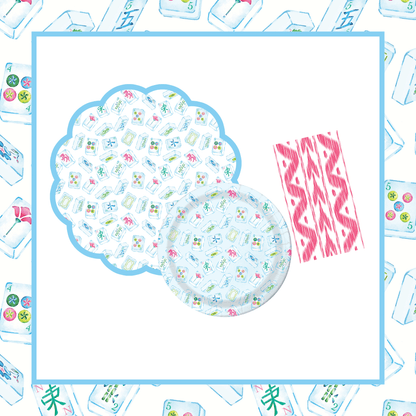 Scalloped round mahjong tile-print paper placemat with a light blue border, paired with a matching round paper plate and a pink ikat linen-feel paper napkin, on a mahjong tile-bordered background.