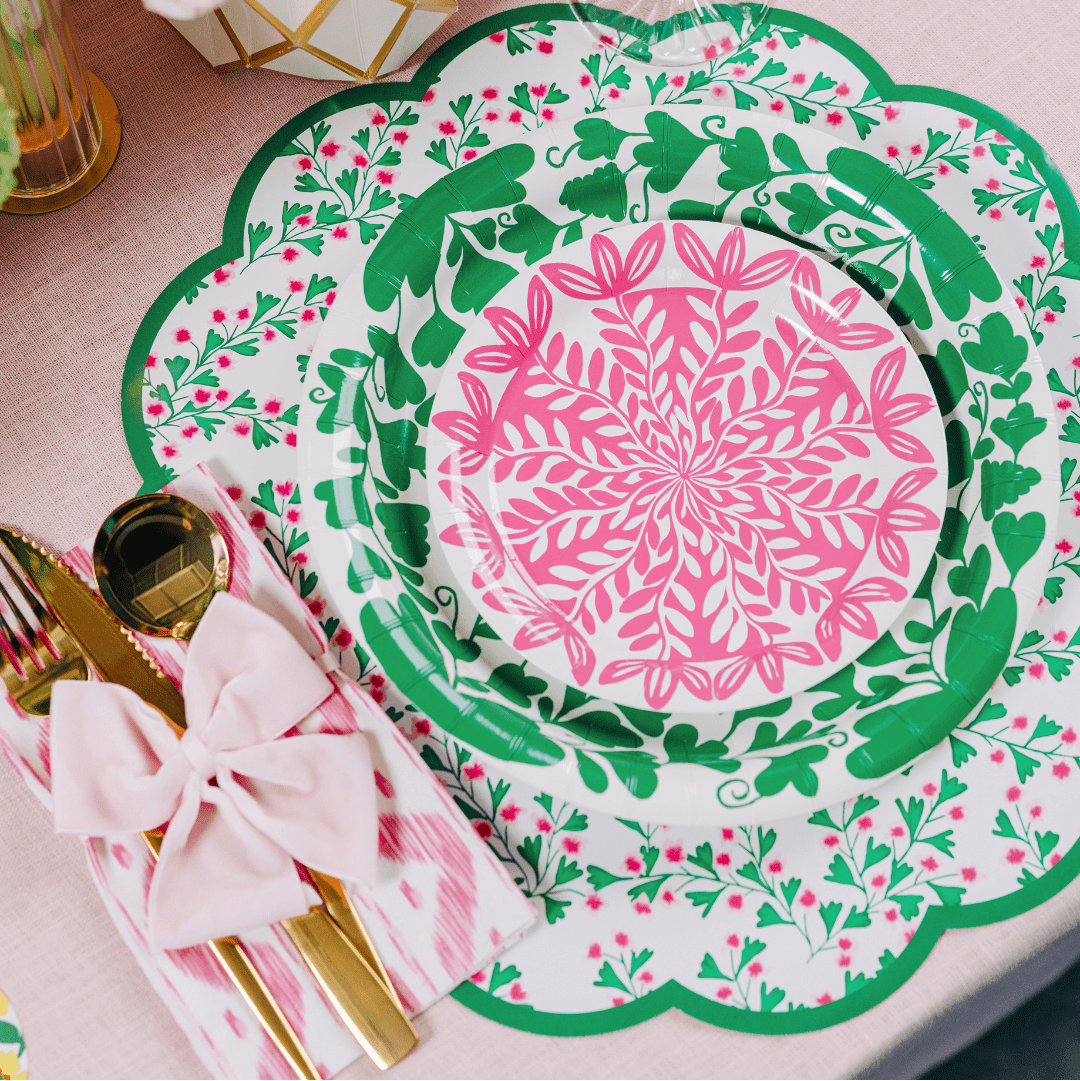 Decorative floral plates with pink and green patterns on a floral paper table setting.