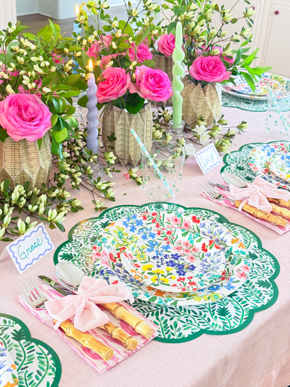 Decorative table setting with floral centerpieces, colorful plates, and pink napkins.