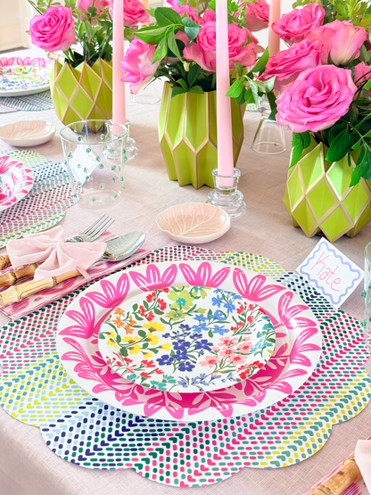 Decorative table setting with floral plates, pink candles, and colorful placemats.