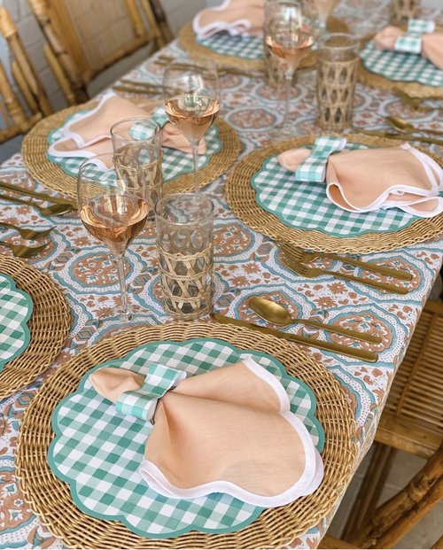 Table with green gingham paper placemats and coral napkins and bow tie napkin rings