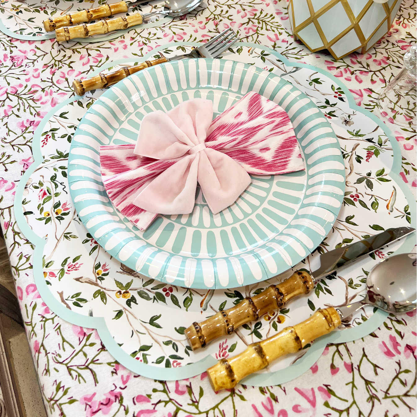 Elegant table setting with floral tablecloth, striped plates, and decorative napkins.