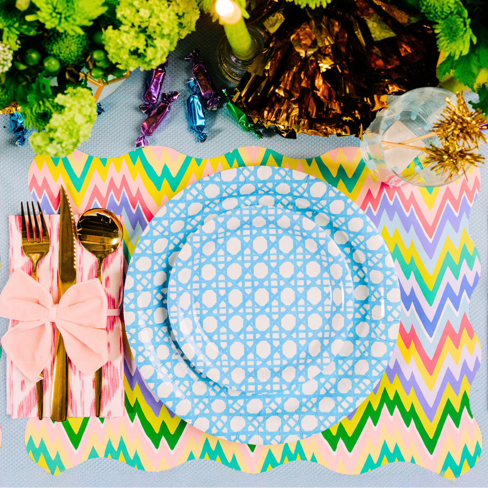 Colorful zigzag placemat with a blue  and white, gold cutlery, and decorative elements on a table.
