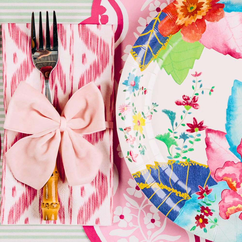 Colorful floral plate with a pink bow and fork on a matching pink napkin.