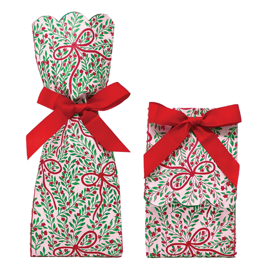 Two paper gift bag kits in a red and green botanical bow print, shown tied as a tall wine bag with scalloped top and a shorter gift bag, each with a red ribbon bow