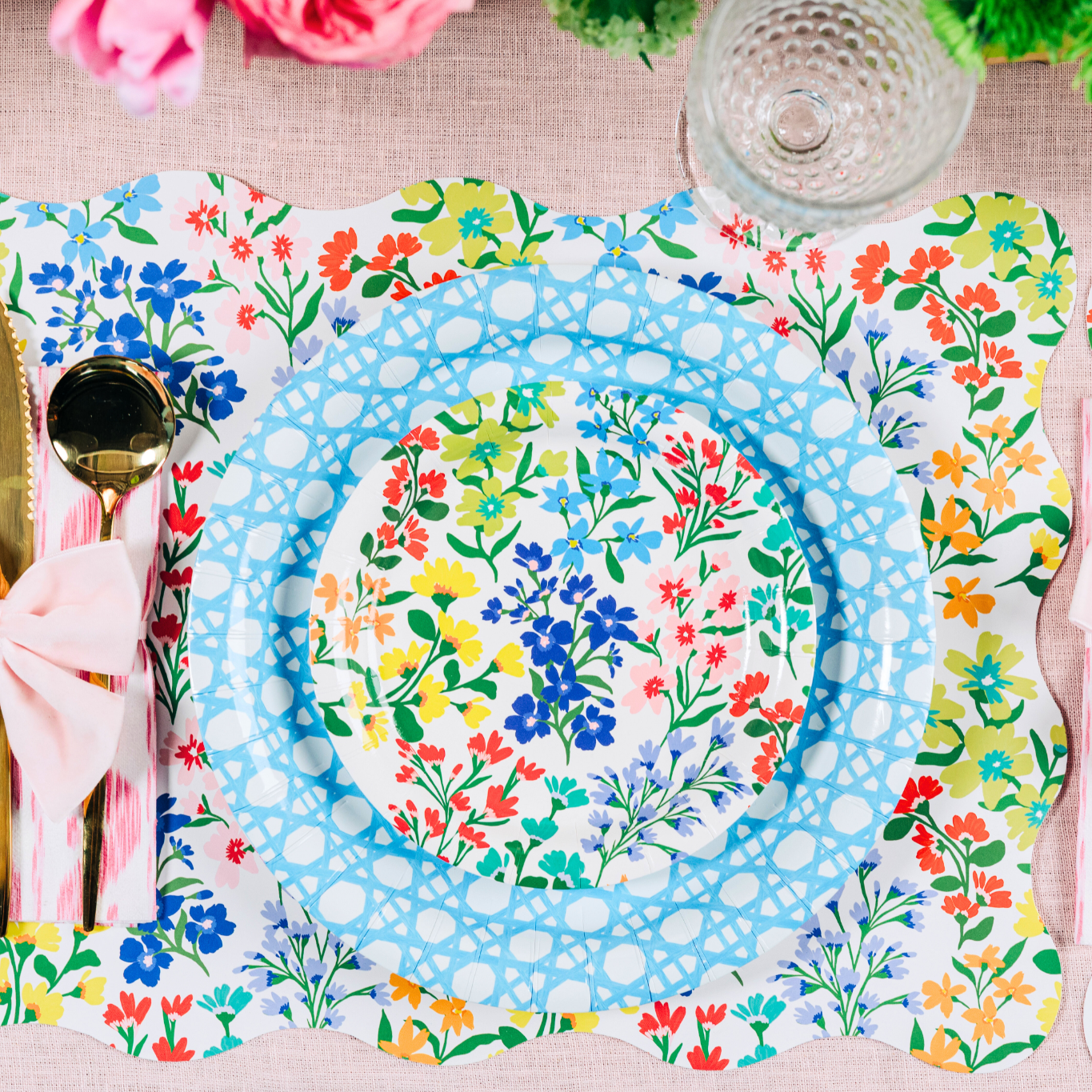 Colorful floral and blue paper plates on a floral placemat with cutlery