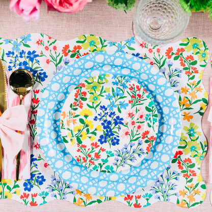 Colorful floral and blue paper plates on a floral placemat with cutlery