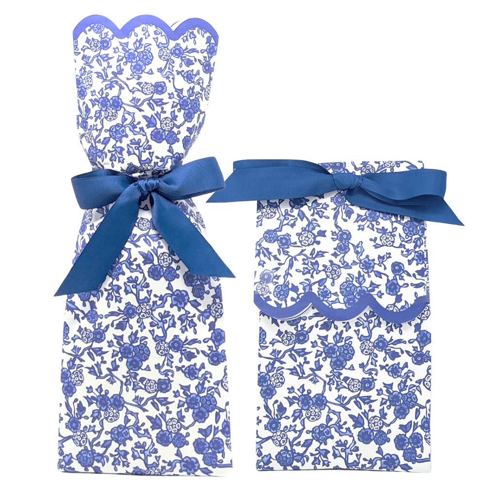 Two paper gift bag kits in a blue and white chinoiserie floral print, shown tied as a tall wine bag and a shorter gift bag, each with a blue ribbon bow