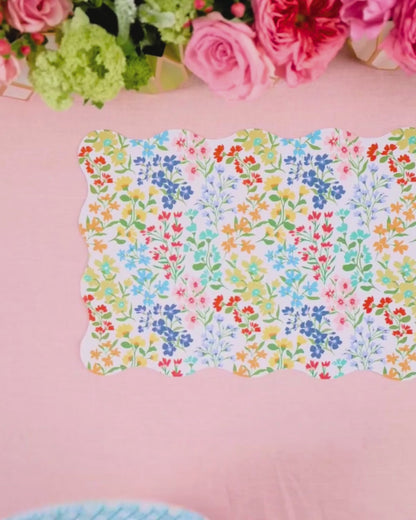 Video showing a multicolor wildflower scalloped placemat being layered with a light blue cane-weave dinner plate and a multicolor wildflower dessert plate