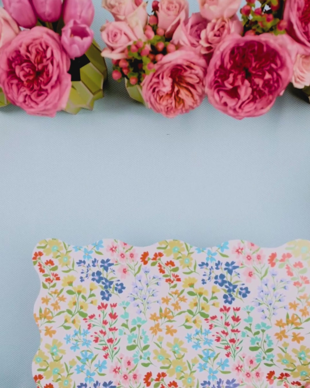 Video showing a multicolor wildflower scalloped placemat being layered with a pink botanical leaf-print dessert plate