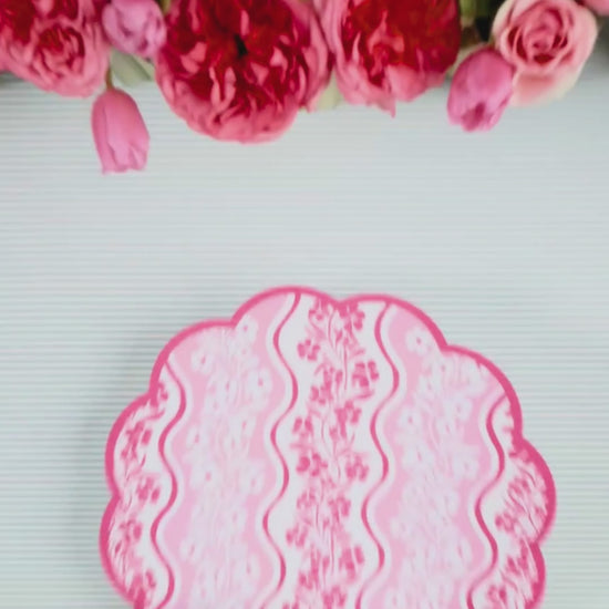 Video showing a pink wavy-stripe floral scalloped placemat being layered with a mint green abstract floral dinner plate