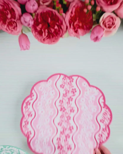 Video showing a pink wavy-stripe floral scalloped placemat being layered with a mint green abstract floral dinner plate
