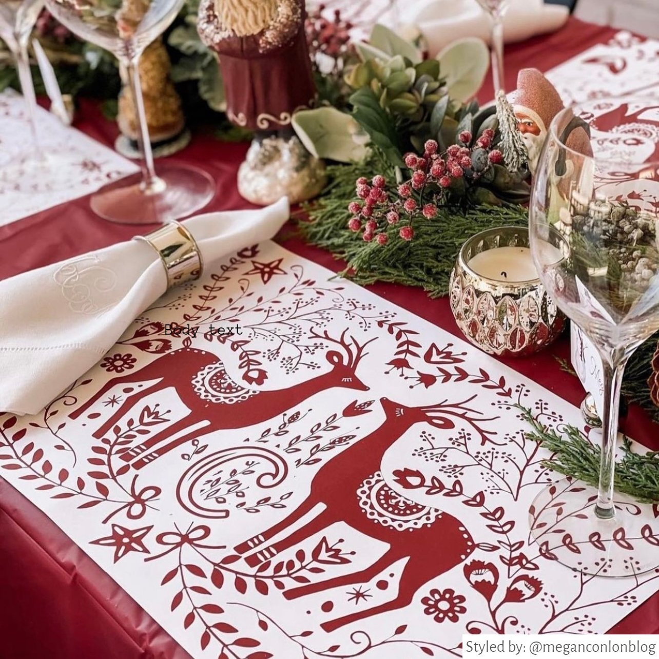 Table setting with red and white reindeer personalized paper placemat on a red tablecloth with various red and green Christmas table decor