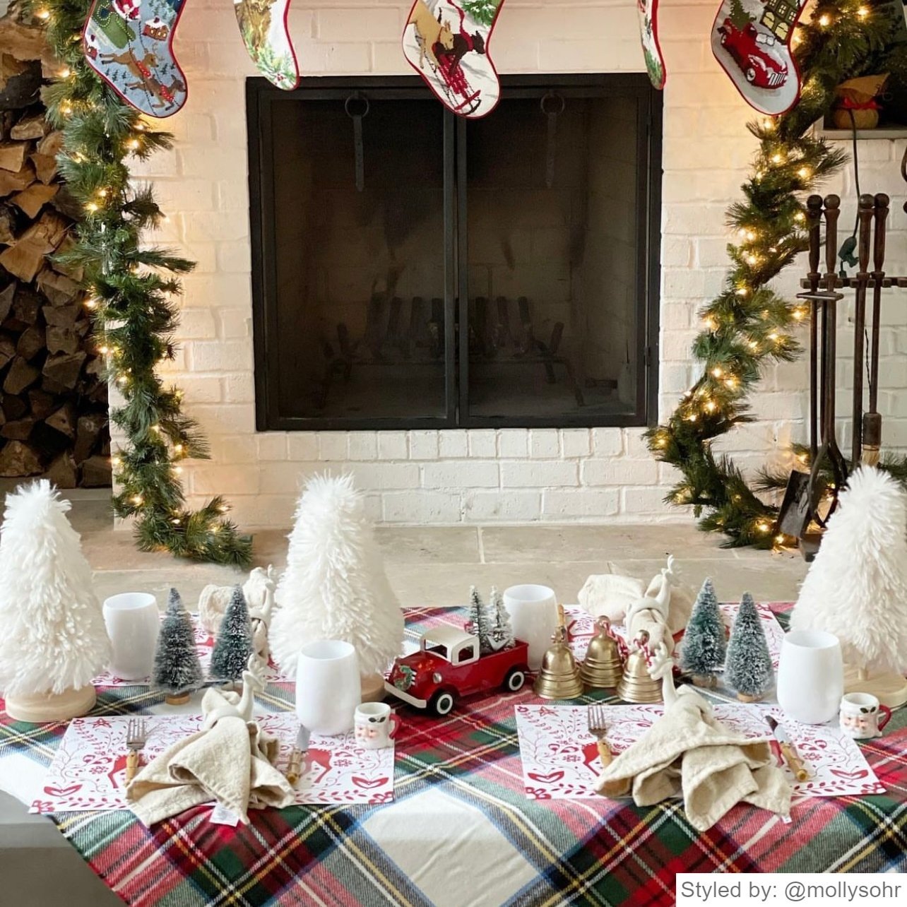 Christmas spread in front of a fire place with red and white Reindeer Paper Placemats and red, white and green holiday decor.