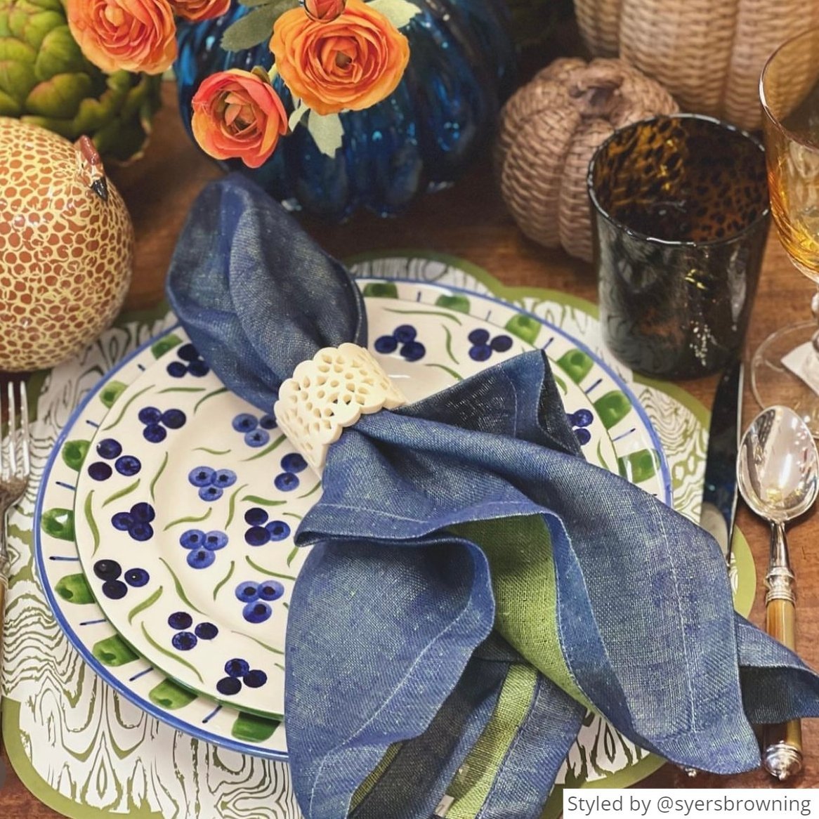 Green wood paper placemat layered with green and white plates and a blue denim napkin