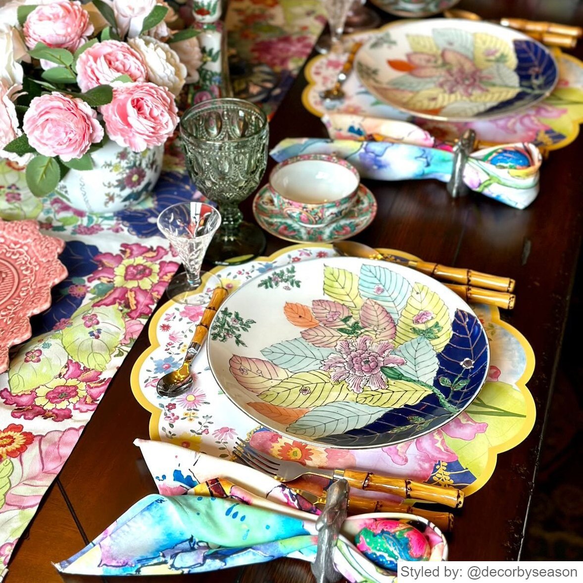 Table setting with tobacco leaf round scalloped paper placemats layered with a tobacco leaf plate on a wood table