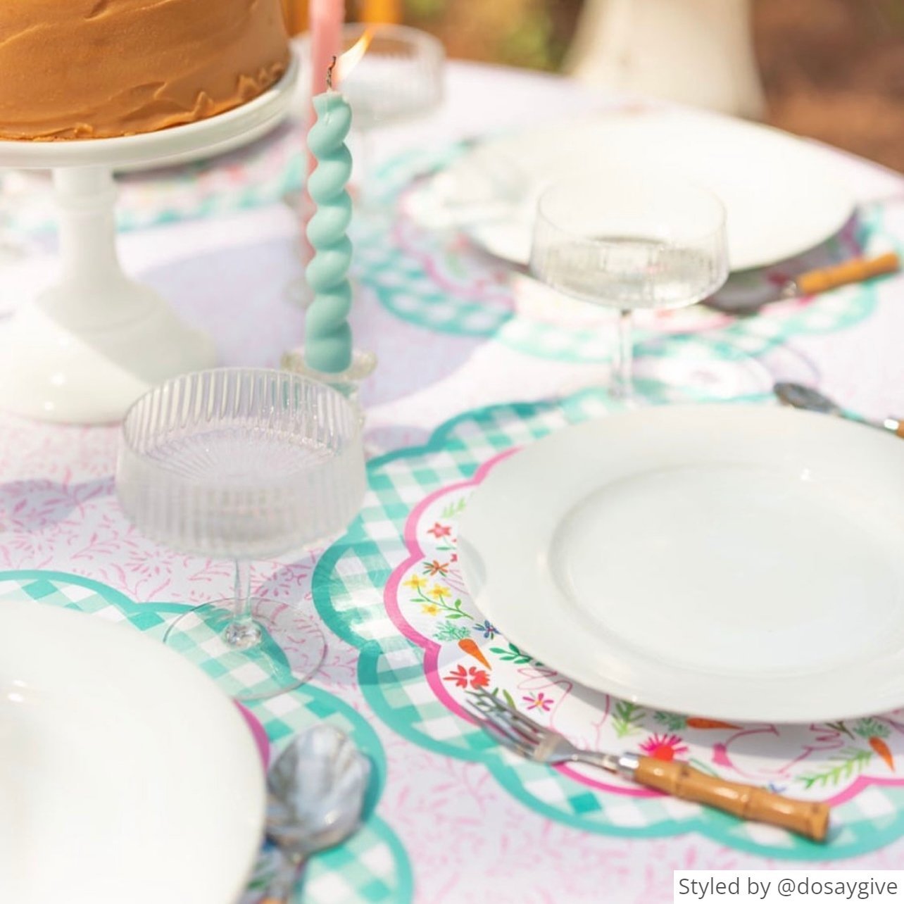 Table setting with a green gingham scalloped round paper placemat layered with a round bunny paper charger and white plate