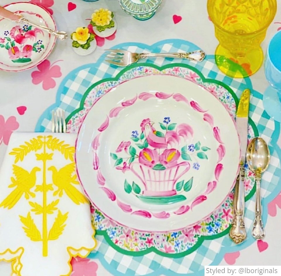 Green gingham scalloped round paper placemat layered with a multicolored floral paper charger and a pink and white china plate