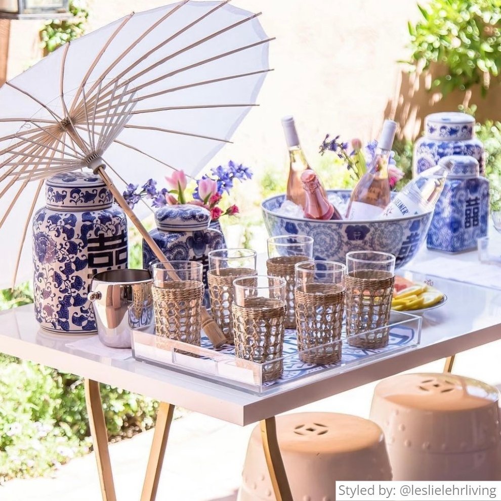 Outdoor table setting with a serving tray, umbrella and bottles of rose