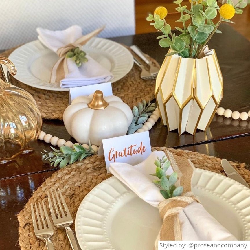 Thanksgiving table setting with gold and white centerpieces on a wooden table