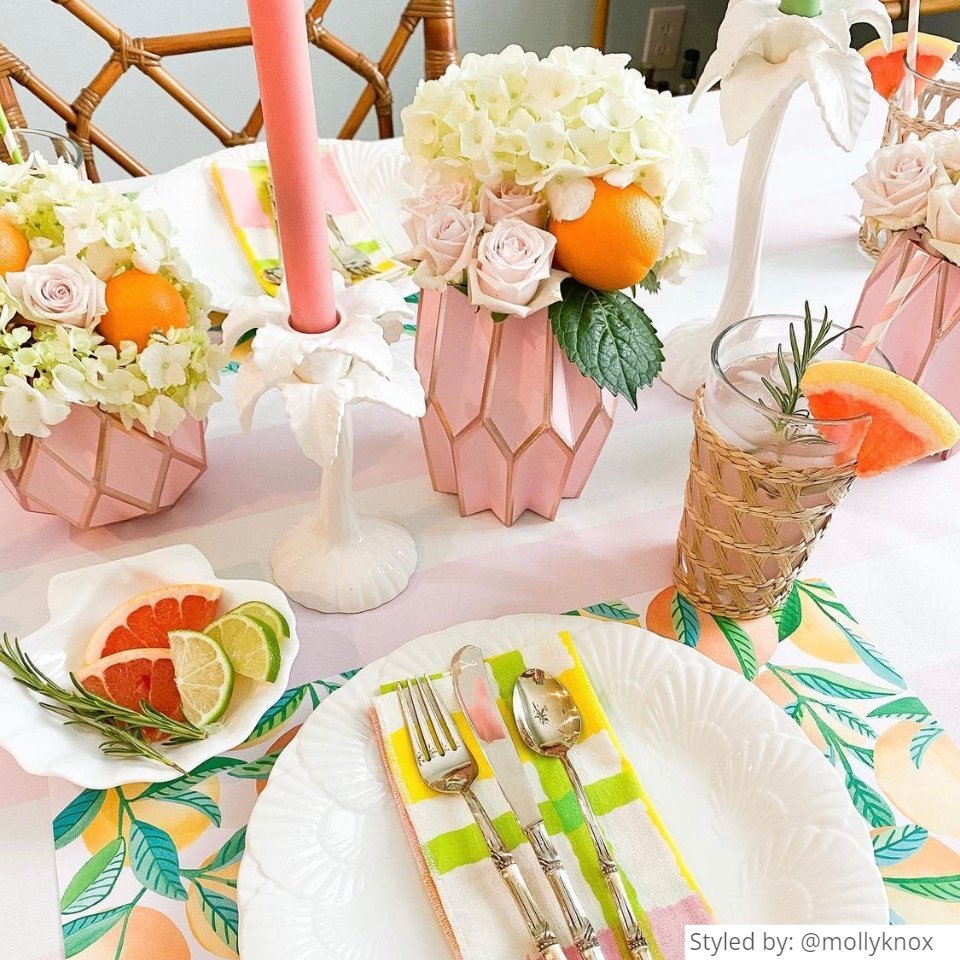 Table setting with orange patterned paper placemats and pink vase wraps