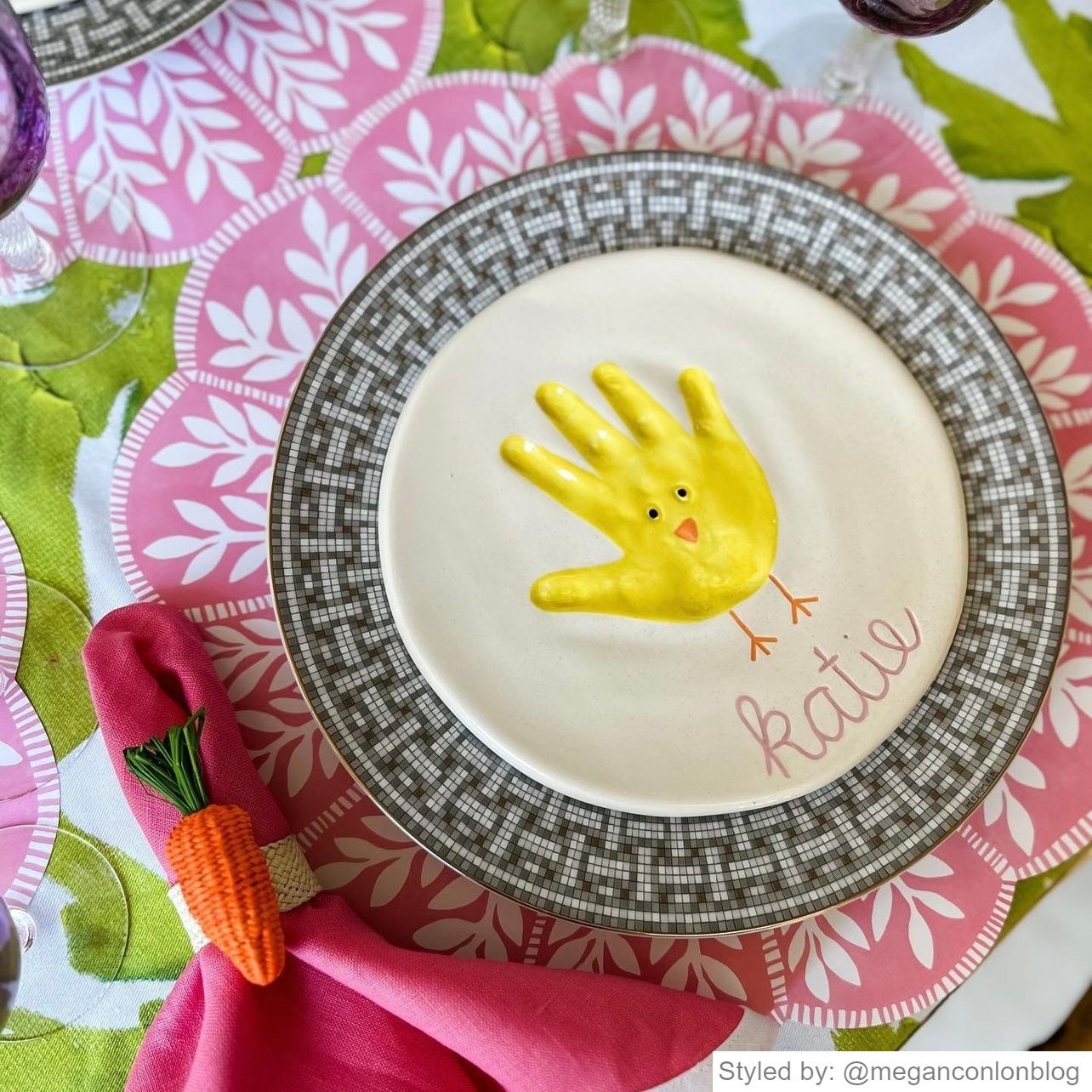 Pink and white scalloped round paper placemat layered with plates and a hot pink napkin with a carrot napkin ring