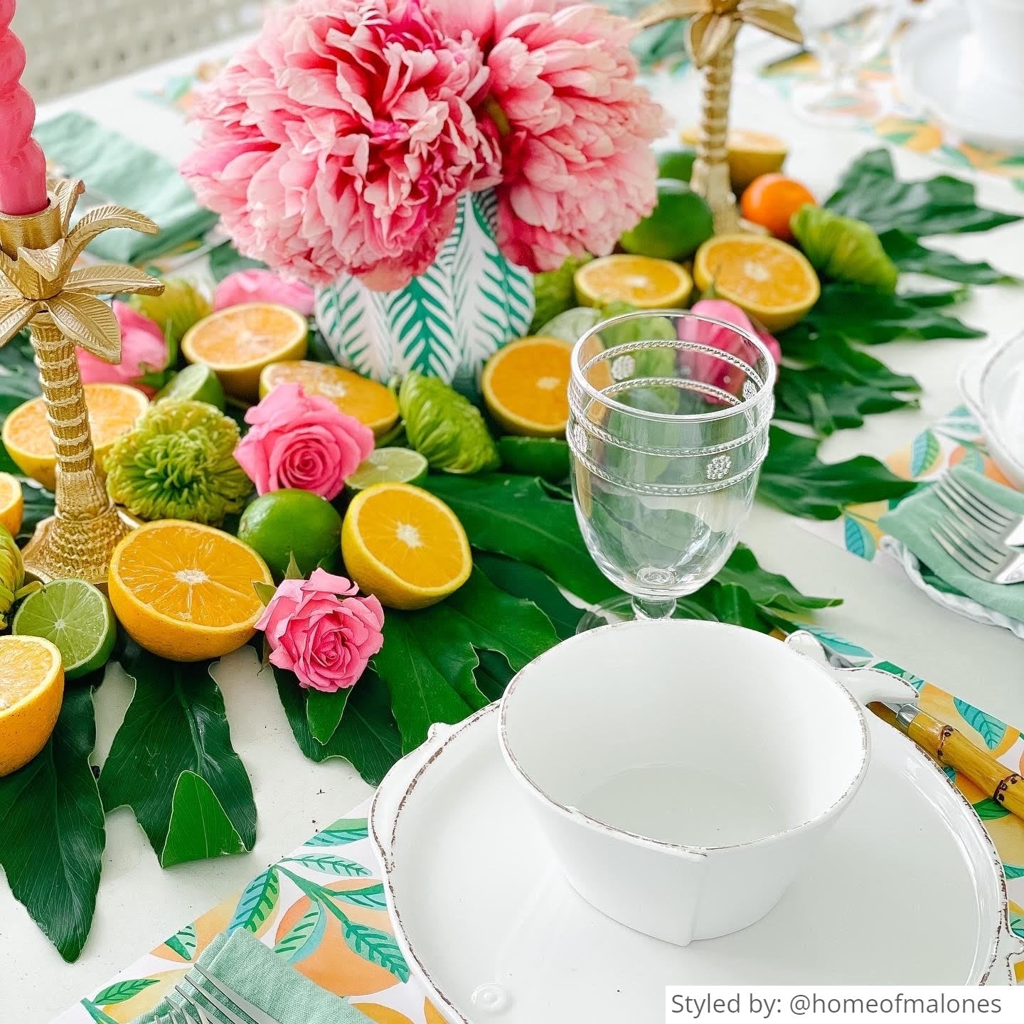 Summer table setting with an orange patterned paper placemat layered with white plates and teacup