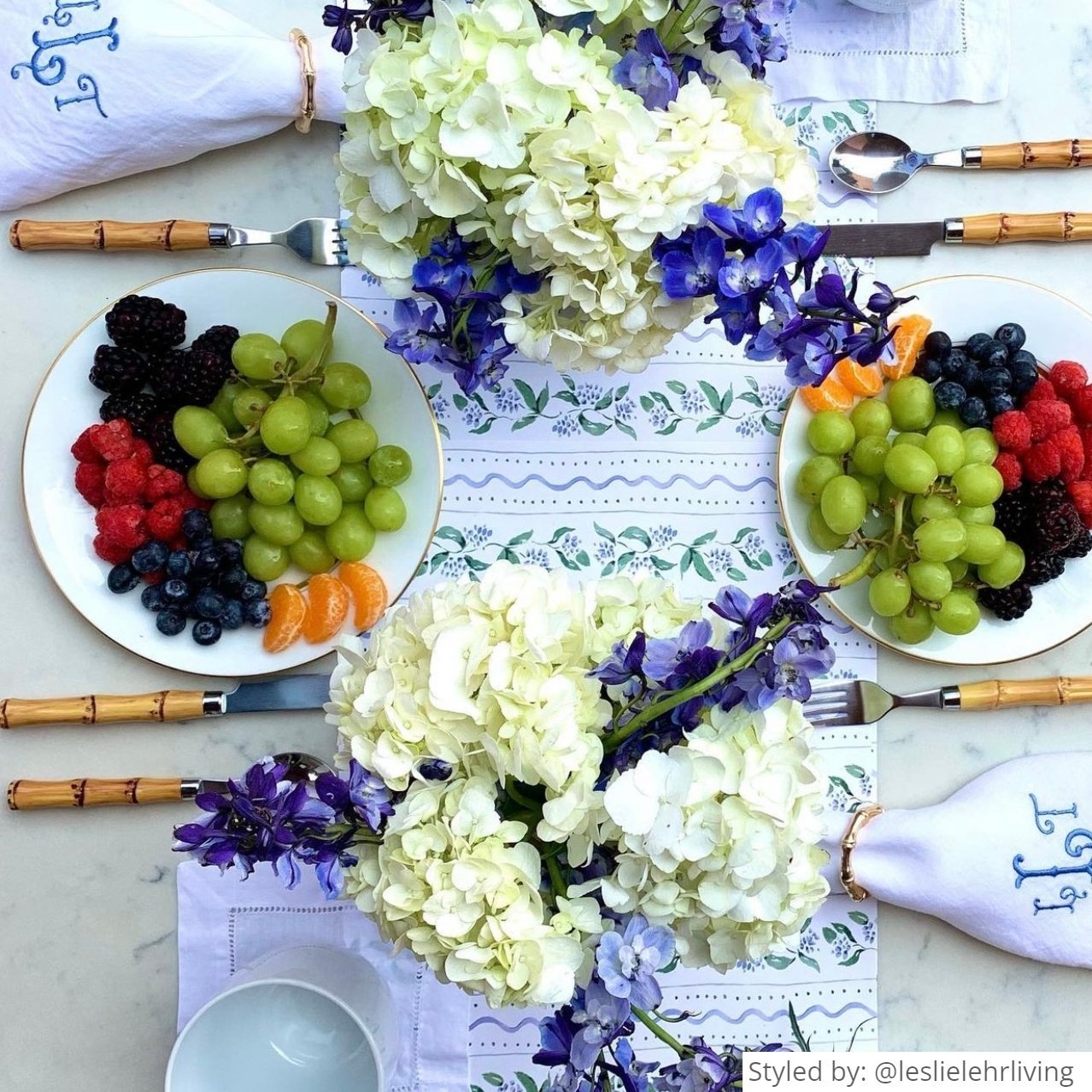 Table setting with a white floral paper tablerunner and fresh fruit and flowers
