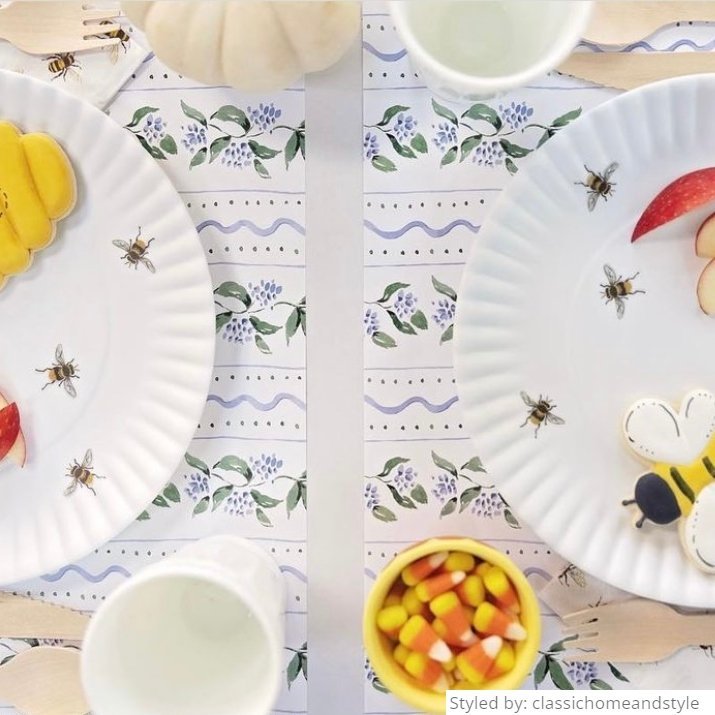 Close up table setting of white floral paper placemats layered with bee paper plates and cookies