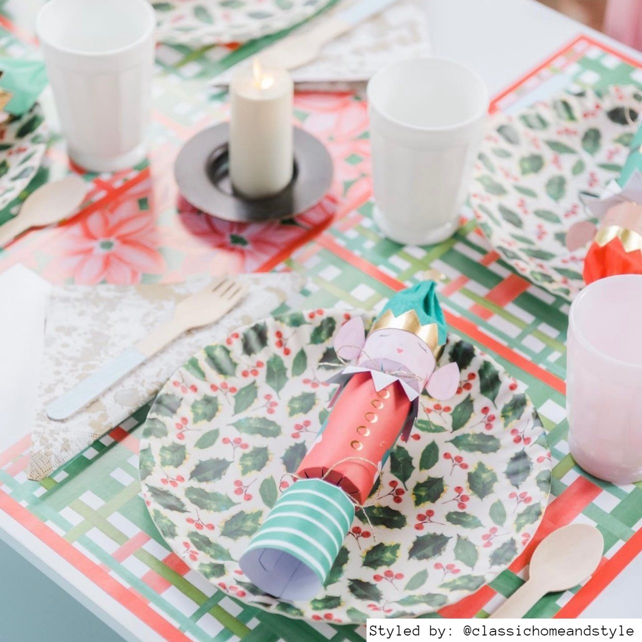 Table setting with red and green plaid paper placemats layered with a red and green holly berry plate and firecrackers shaped like nutcrackers