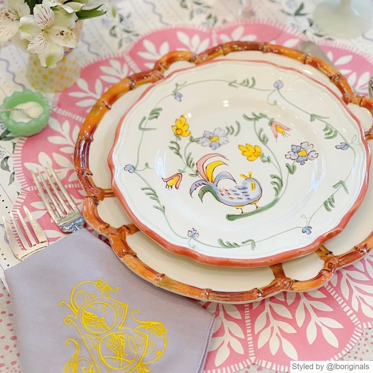 Pink and white scalloped round paper placemat layered with bamboo plates and china