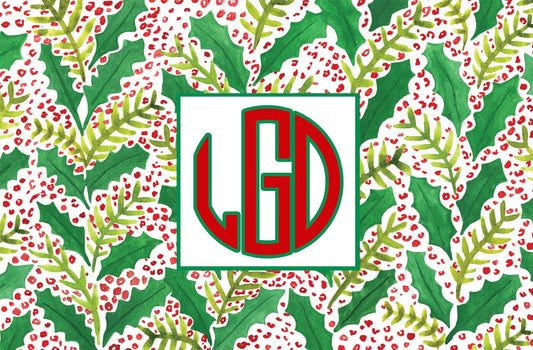 Paper placemat featuring a red and green holly berry pattern with a red and green square monogram