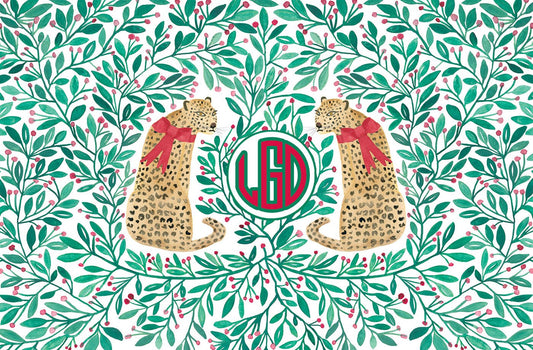 Paper placemat featuring a red and green holly berry pattern with leopards and a red and green monogram