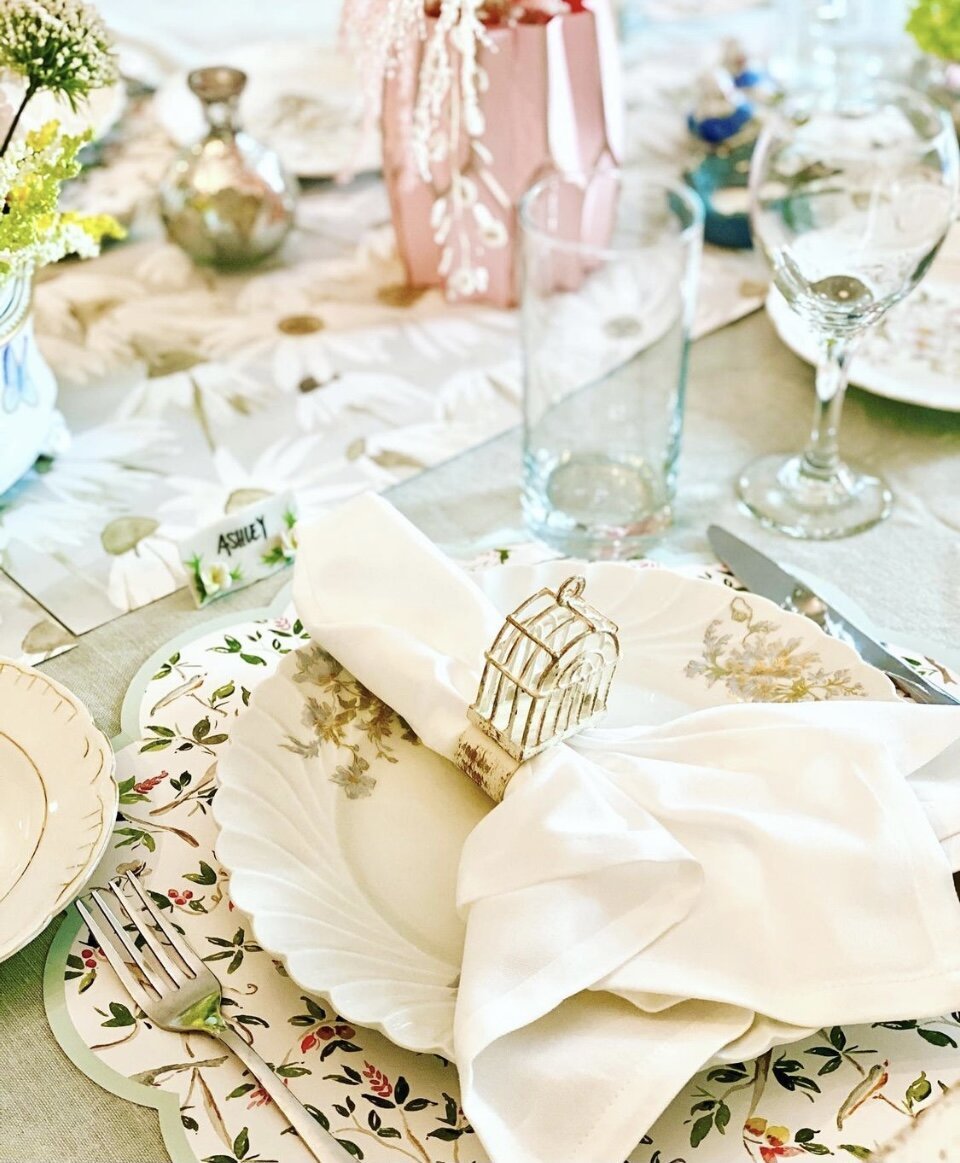 Table setting with round chinoiseire scalloped paper placemat layered with a white plate and white napkin with a gold napkin ring