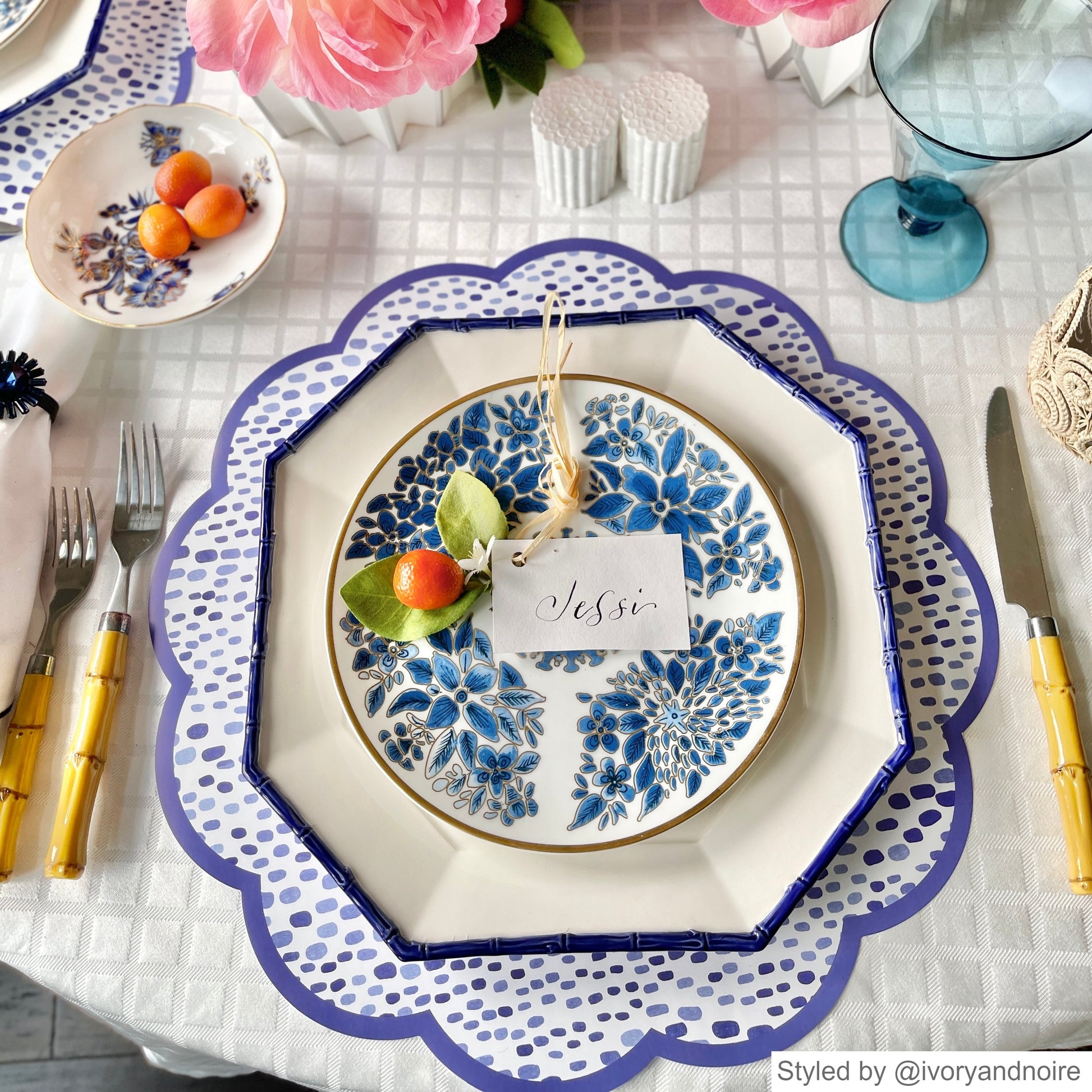 Blue and white dot patterned paper placemat layered with a blue and white hexagonal dish on a white tablecloth