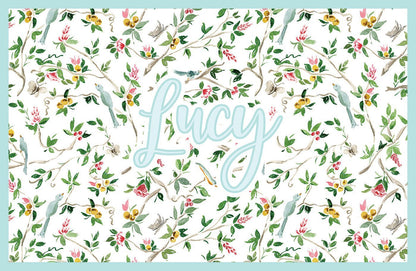 Paper placemat featuring a chinoiserie pattern and light blue personalized name