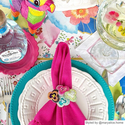 Place setting with tobacco leaf paper placemats layered with blue and white dishes and a pink napkin with a beaded floral napkin ring