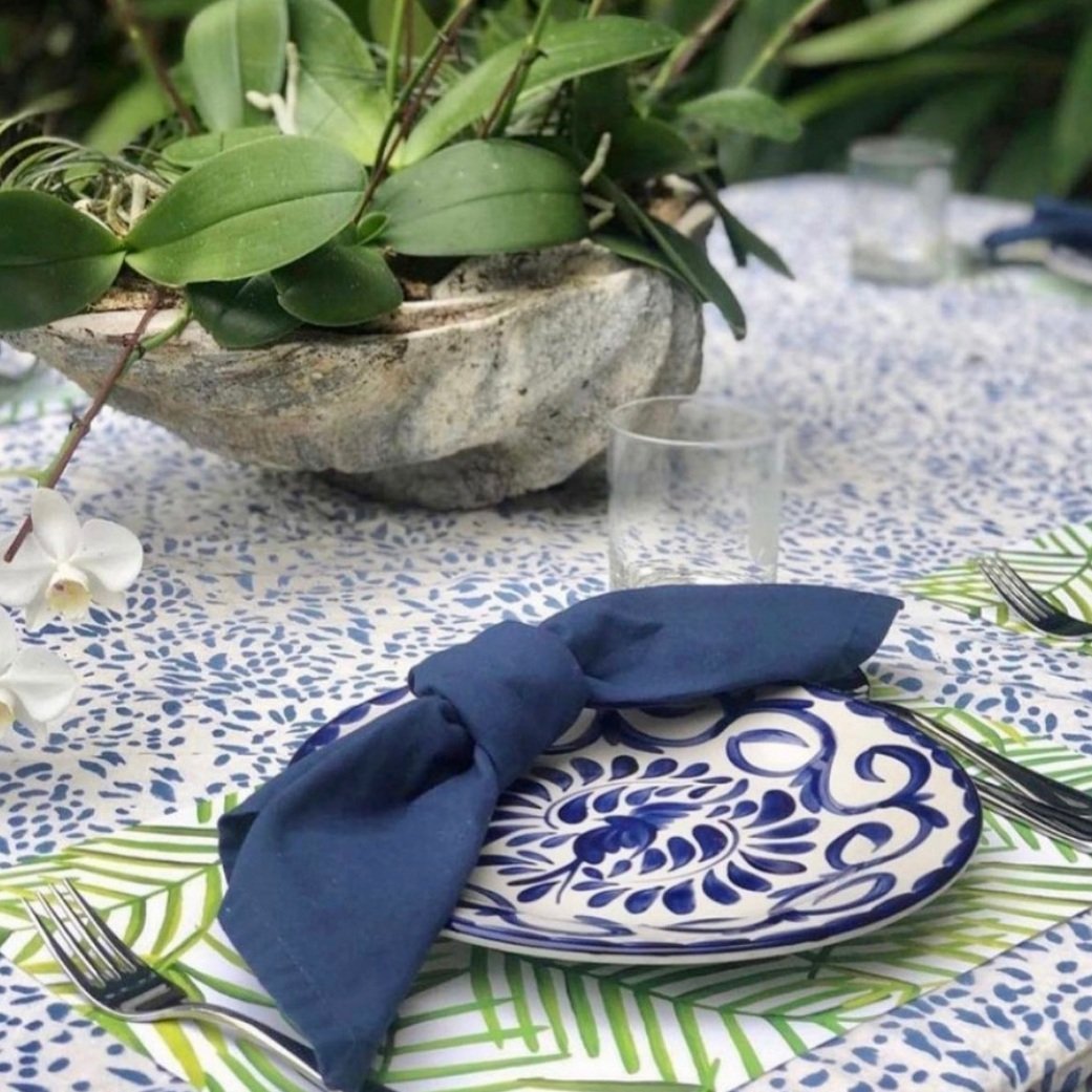 Green leaf paper placemat on picnic table with blue and white dotted tablecloth and blue cloth napkins