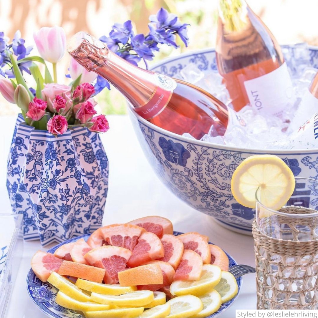 Outdoor table setting with blue and white chinoiserie paper vase and bottles of rose in an ice bowl