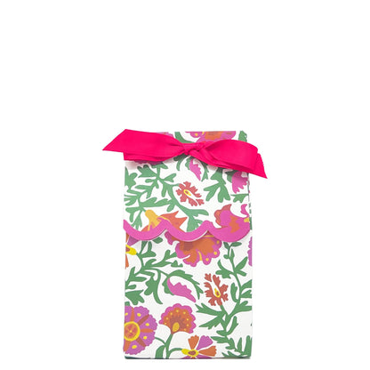 Paper wine bag featuring a pink, green and orange floral design tied as a gift bag with a pink bow